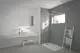 Badezimmer mit heller Wand und Dusche. Eine Wand-WT-Armatur von Ideal Standard ist sichtbar, kombiniert mit einem modernen Waschbecken und einem großen Spiegel.